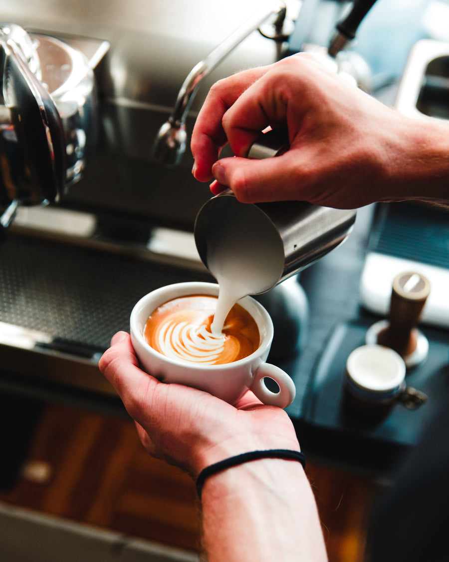 Barista pouring steamed milk over an espresso during a Prepare and Serve session